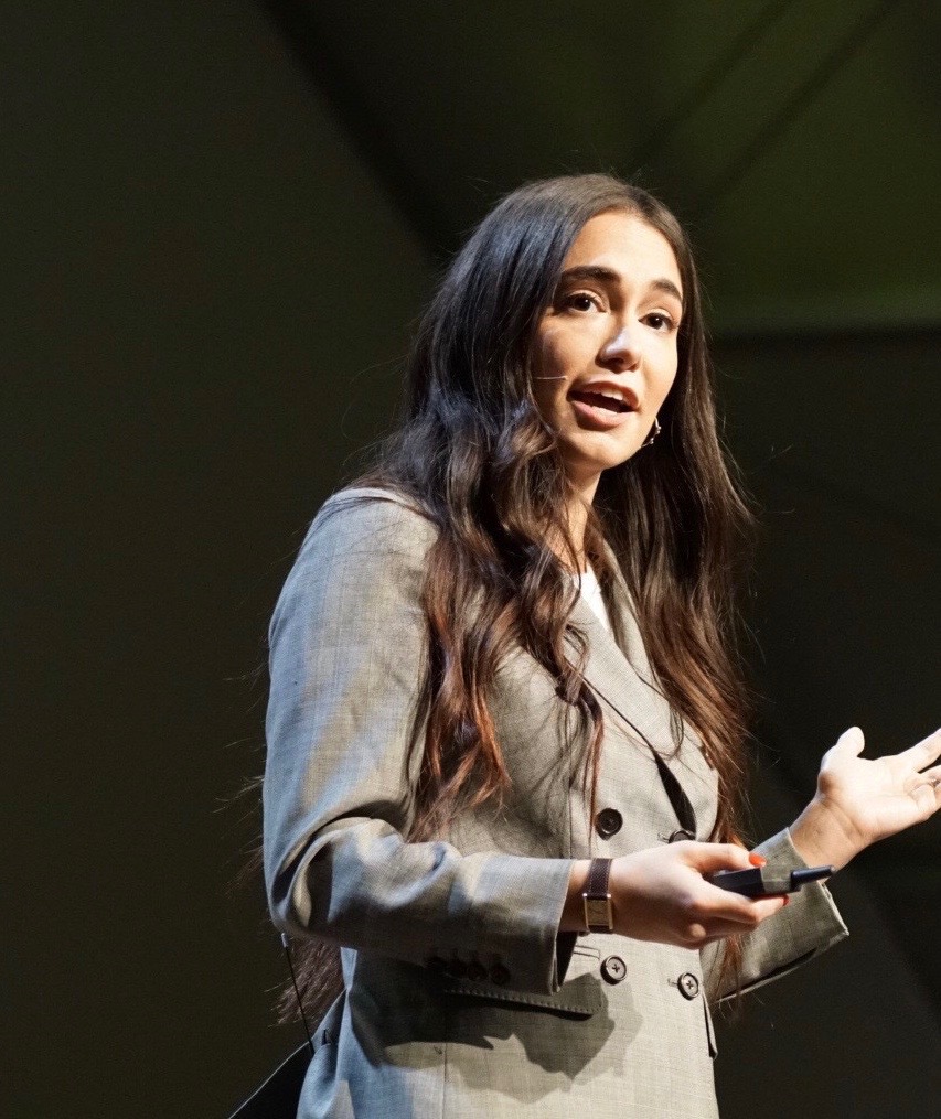 Audrey Gelman, founder of The Six Bells, speaking on stage with a headset microphone at the 2019 Upfront Summit