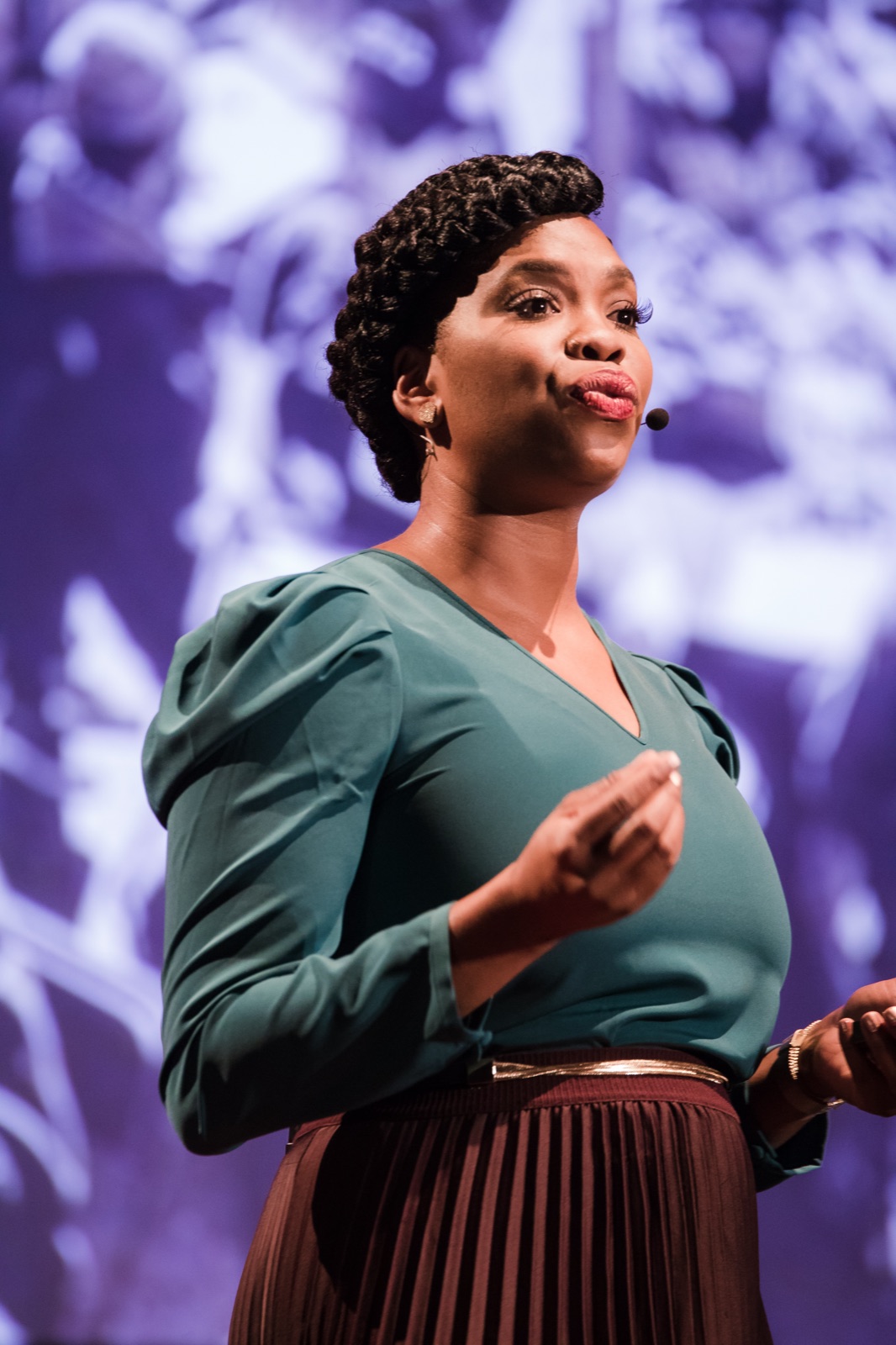 Jasmine Crowe-Houston, founder and CEO of Goodr, speaking on stage at TEDxPeachtree with a headset microphone, wearing a teal blouse